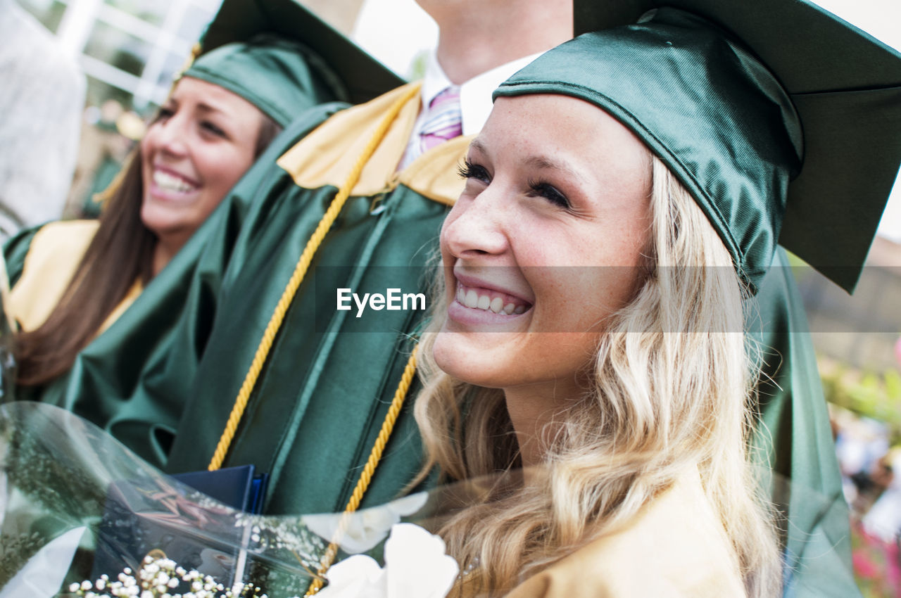 Close-up of happy young woman with friends at graduation ceremony