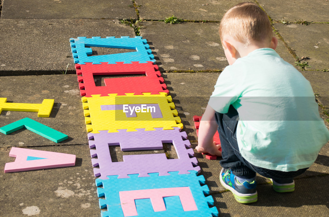 High angle view of boy arranging alphabets on street