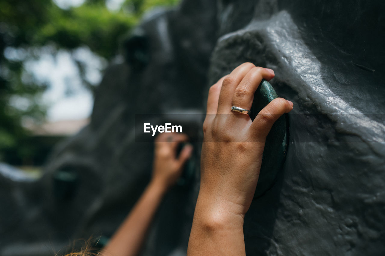 Cropped hand of woman climbing wall