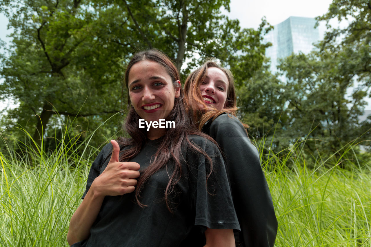 Portrait of cheerful friends standing on field