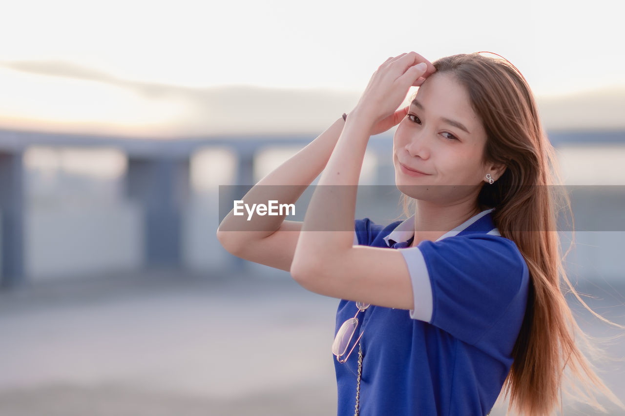 PORTRAIT OF BEAUTIFUL WOMAN STANDING IN FRONT OF A SMILING YOUNG