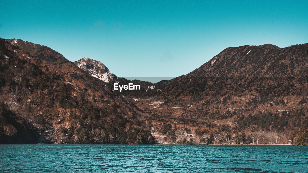 SCENIC VIEW OF SEA AND MOUNTAINS AGAINST CLEAR SKY
