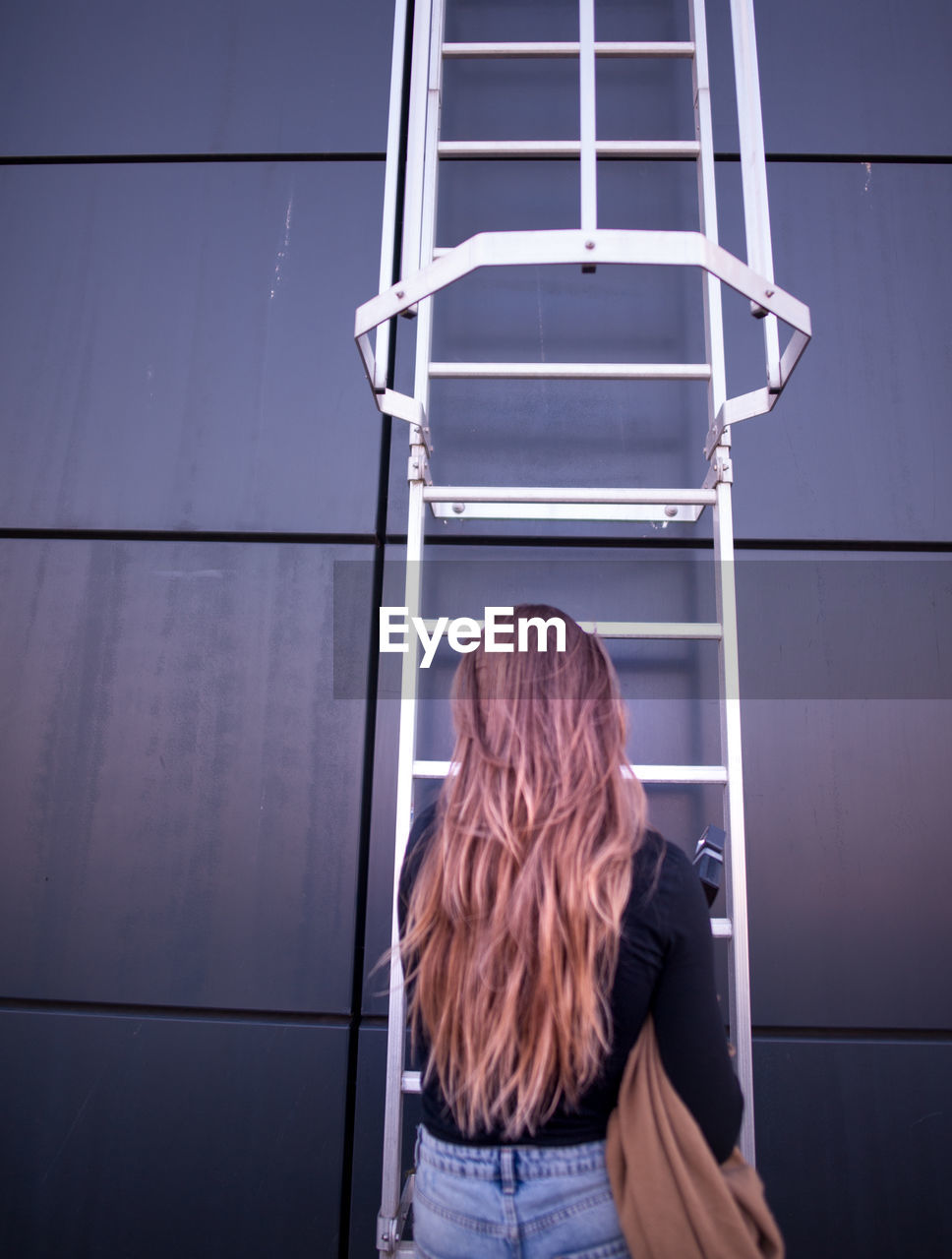 REAR VIEW OF WOMAN SITTING ON THE FLOOR