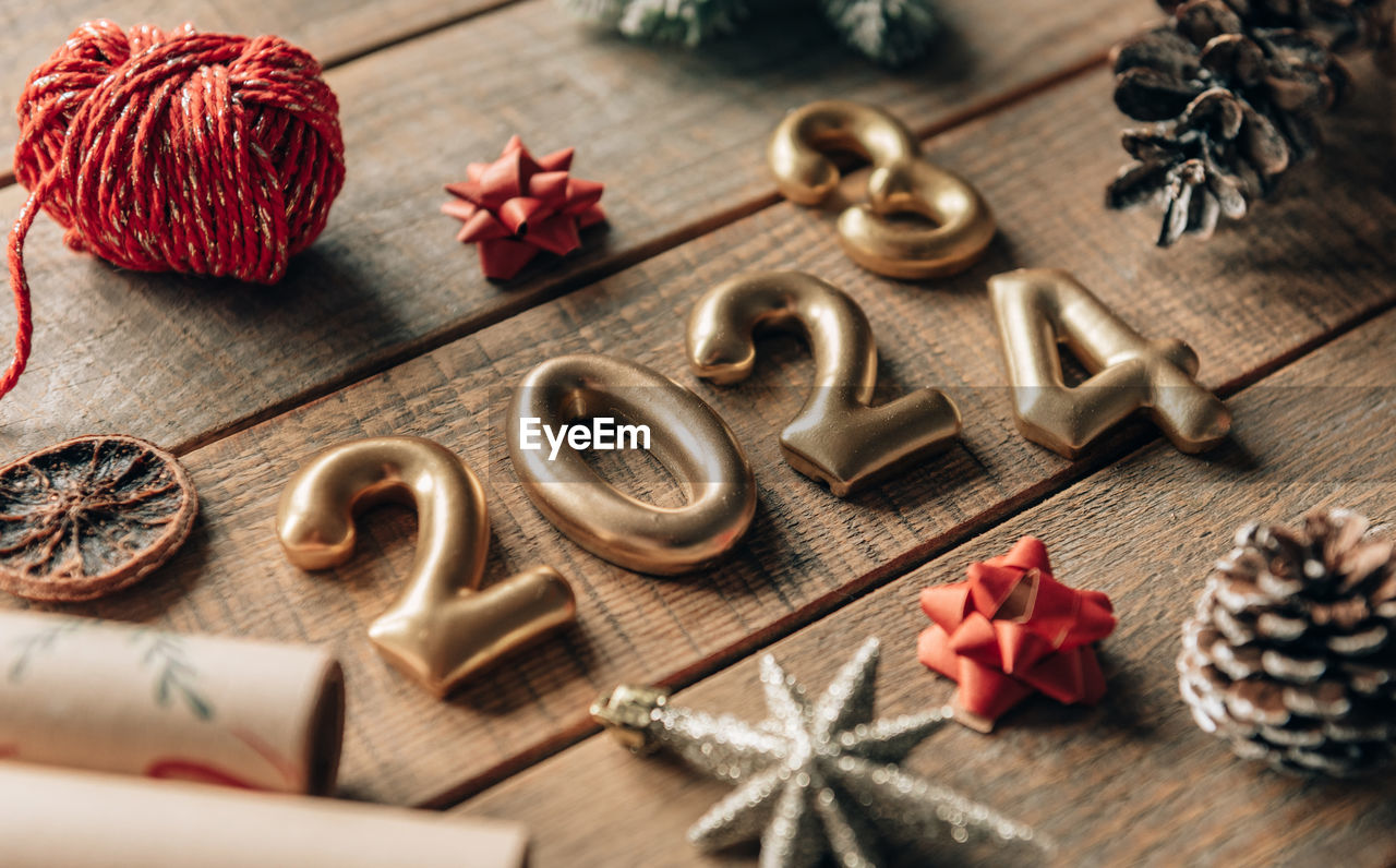 Close-up photo of golden new year 2024 numbers on wooden background with christmas decorations