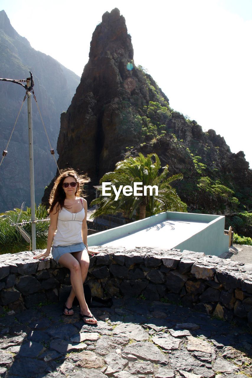 Full length of woman on retaining wall against rock formation at masca