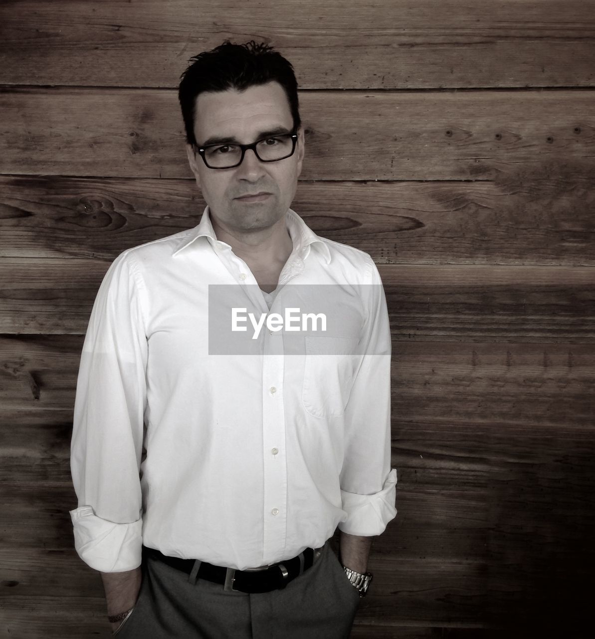 Portrait of businessman standing against wooden wall