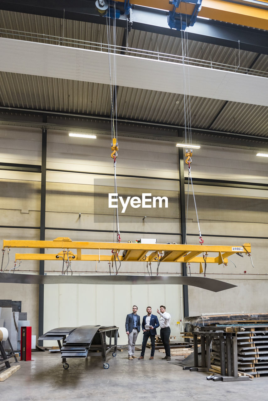 Three men standing on factory shop floor