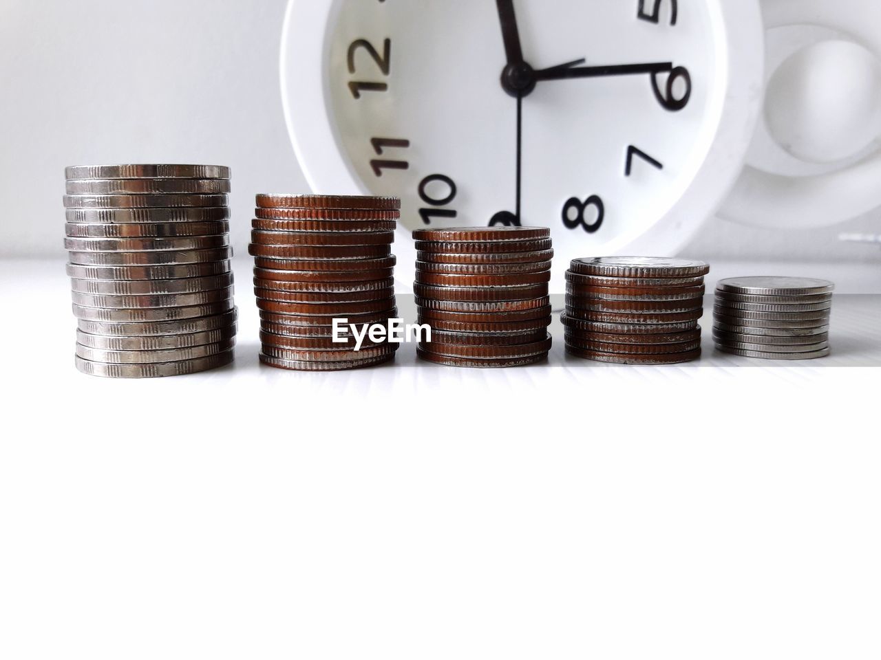 Close-up of coins and alarm clock on table