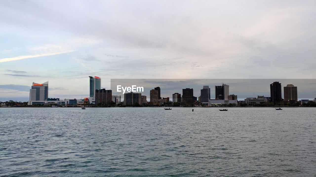 Sea and buildings in city against sky