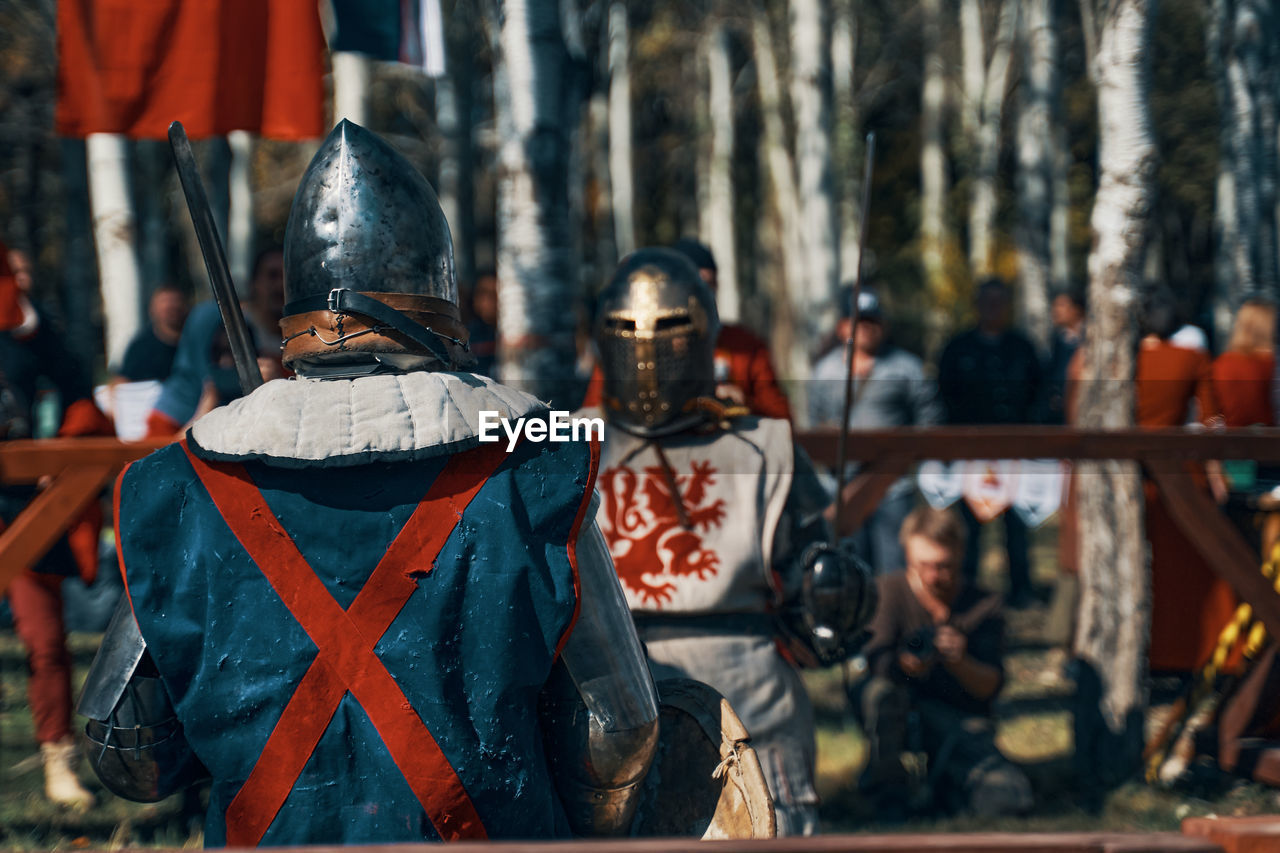 REAR VIEW OF MEN STANDING AGAINST WALL