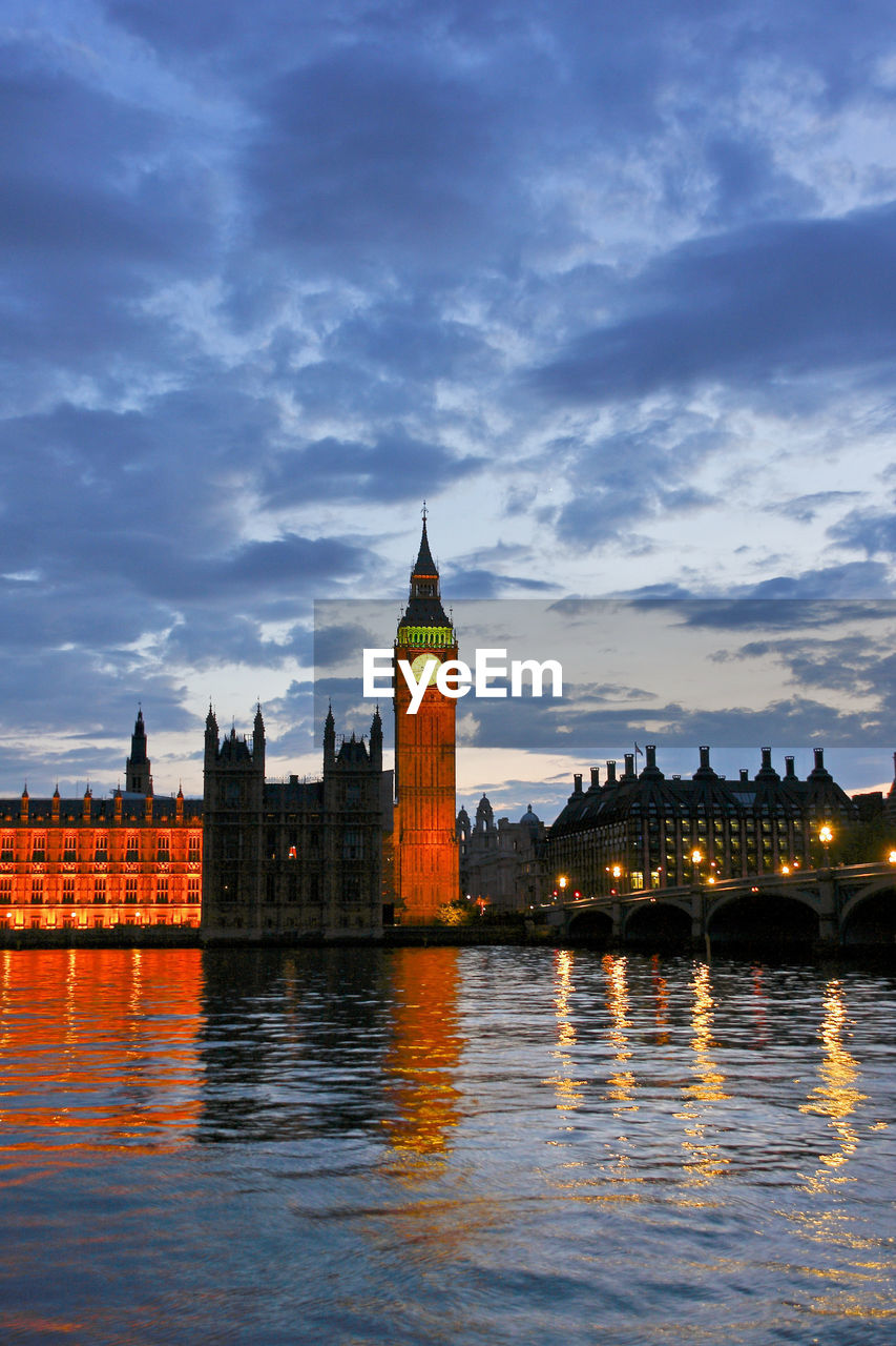 Illuminated  westminster buildings in london at waterfront against cloudy sky