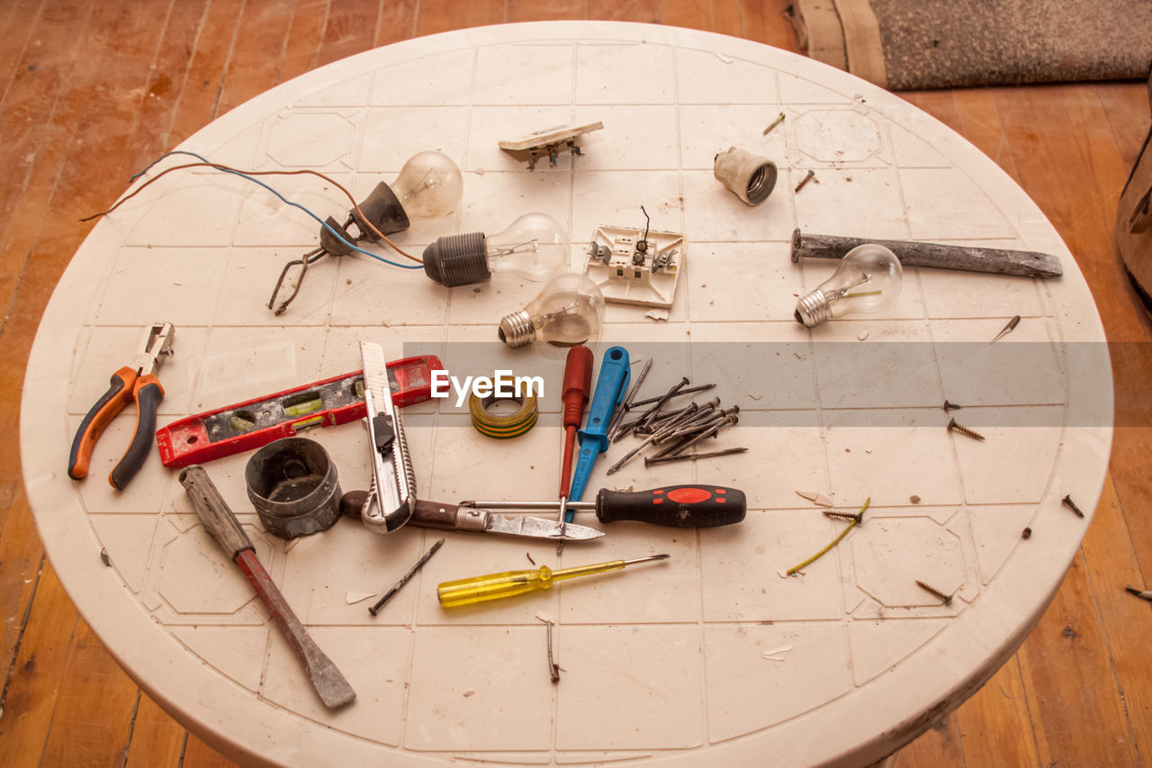 Flat renovation, master of his tools scattered all over the table, pliers, screwdriver, nails, bulbs