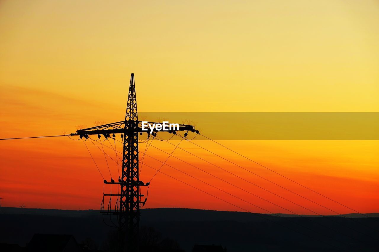 Silhouette electricity pylon against romantic sky at sunset