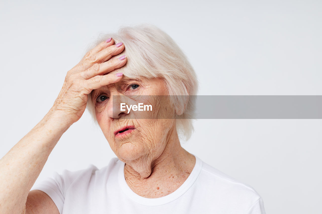 Portrait of stressed senior woman against white background