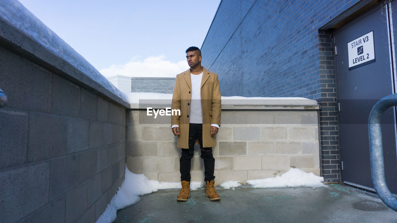 Thoughtful young man standing against railing during winter