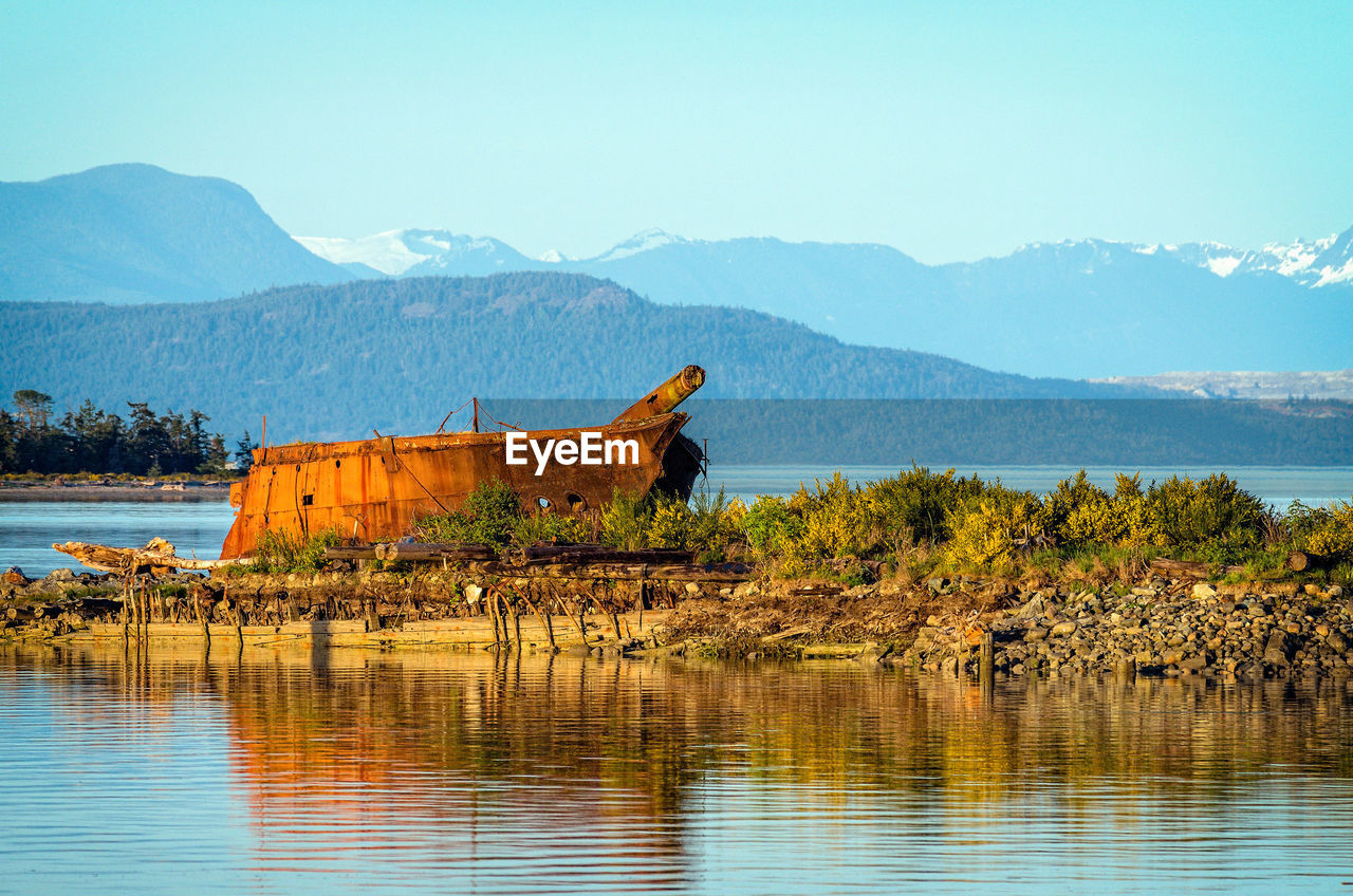 Shipwreck at lakeshore by mountains