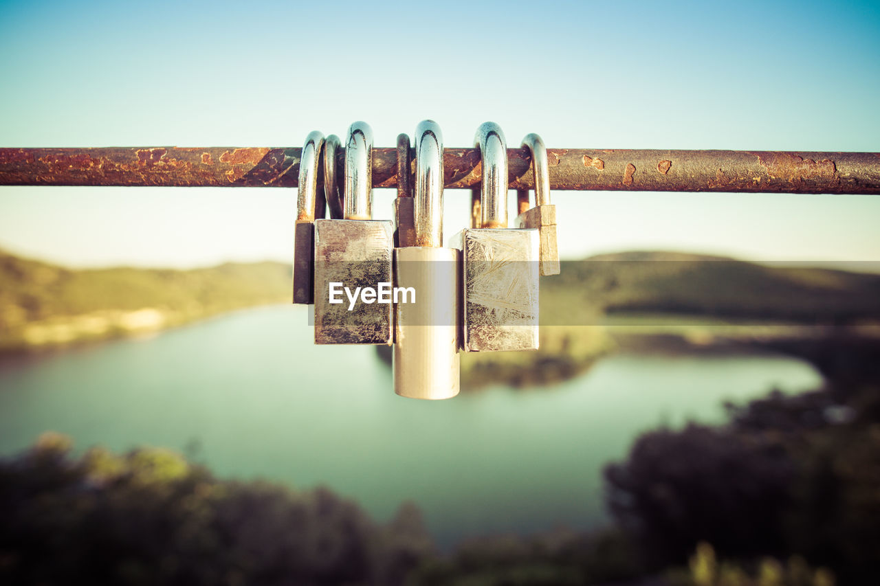 Close-up of padlocks hanging on metal against sky