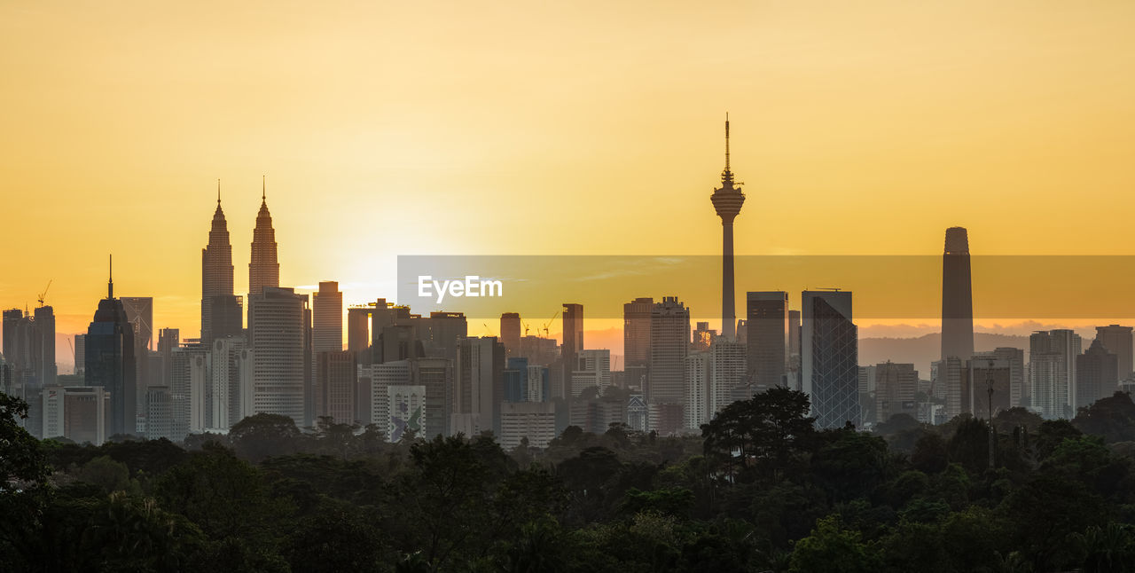 Buildings in city against sky during sunset