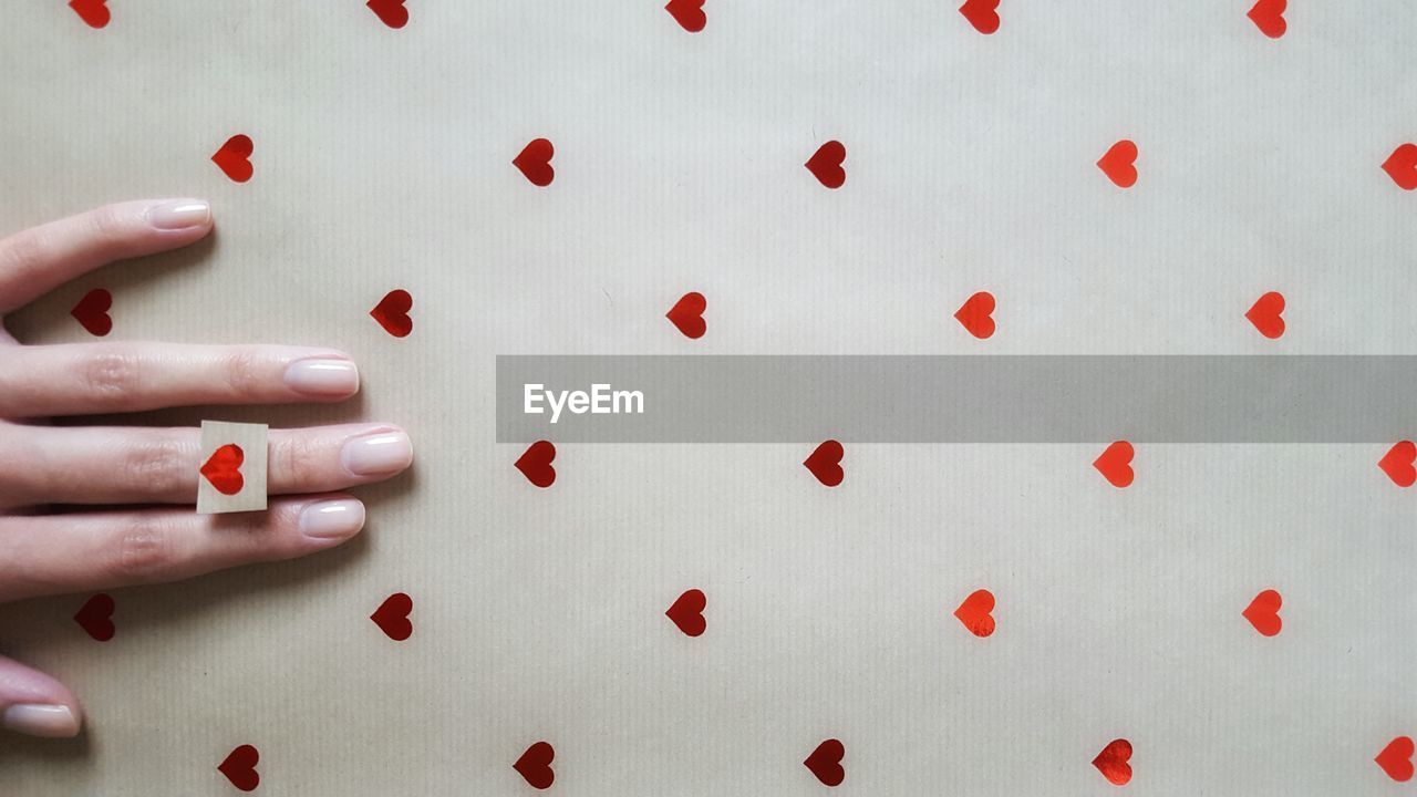 Cropped image of woman hand on paper with heart shapes