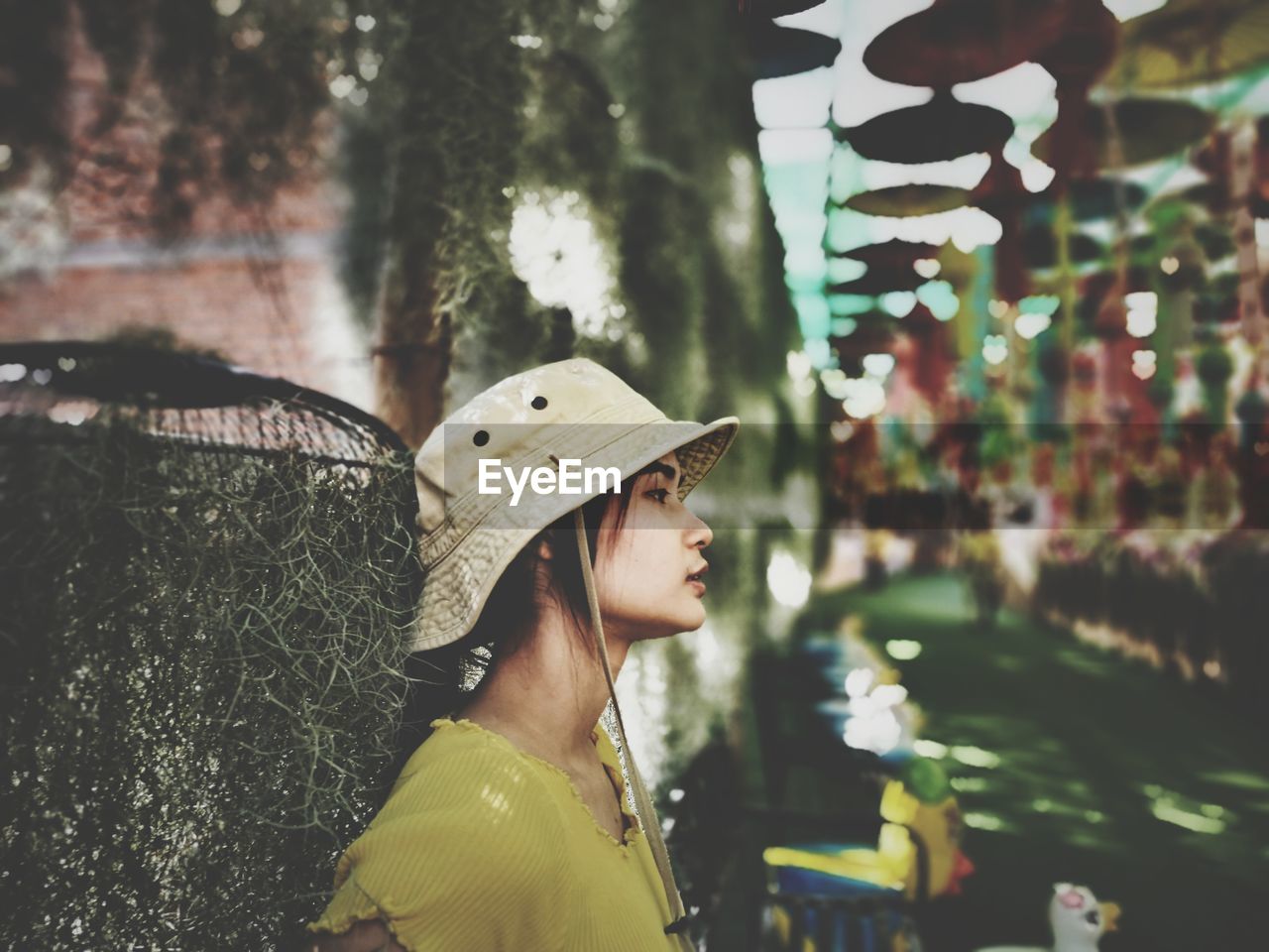 Side view of young woman looking away against trees