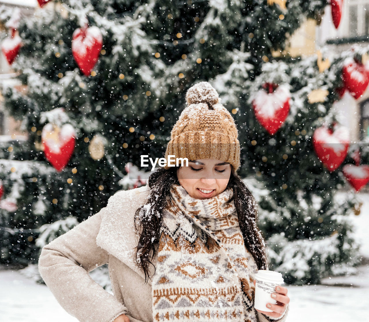 Portrait of a young woman drinking coffee from a paper coffee to go cup. winter, christmas, snowing.