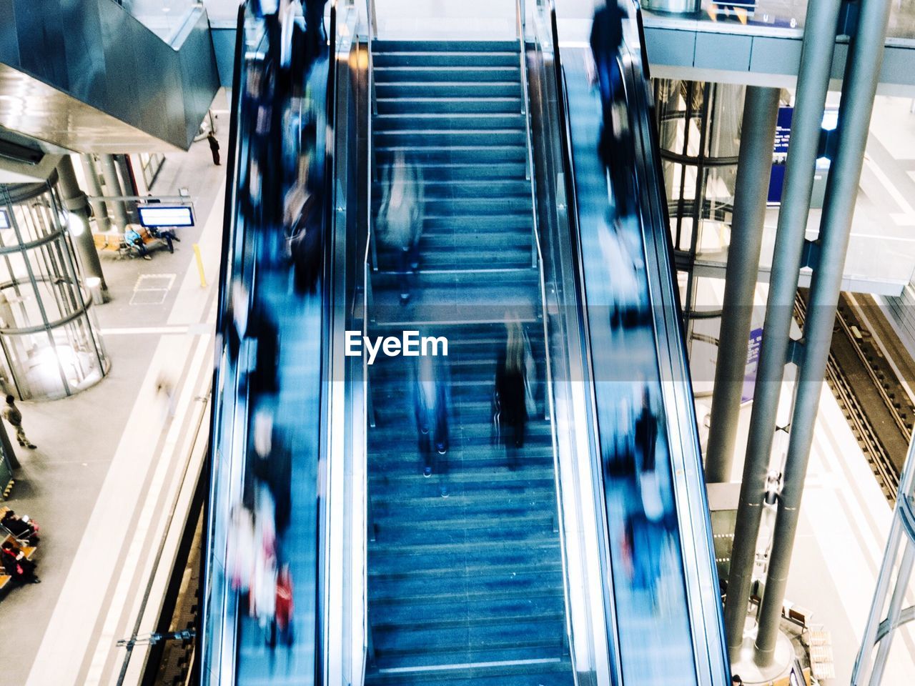 transportation, motion, steps, blurred motion, high angle view, staircase, architecture, steps and staircases, indoors, built structure, modern, blue, subway station, illuminated, no people, day, city