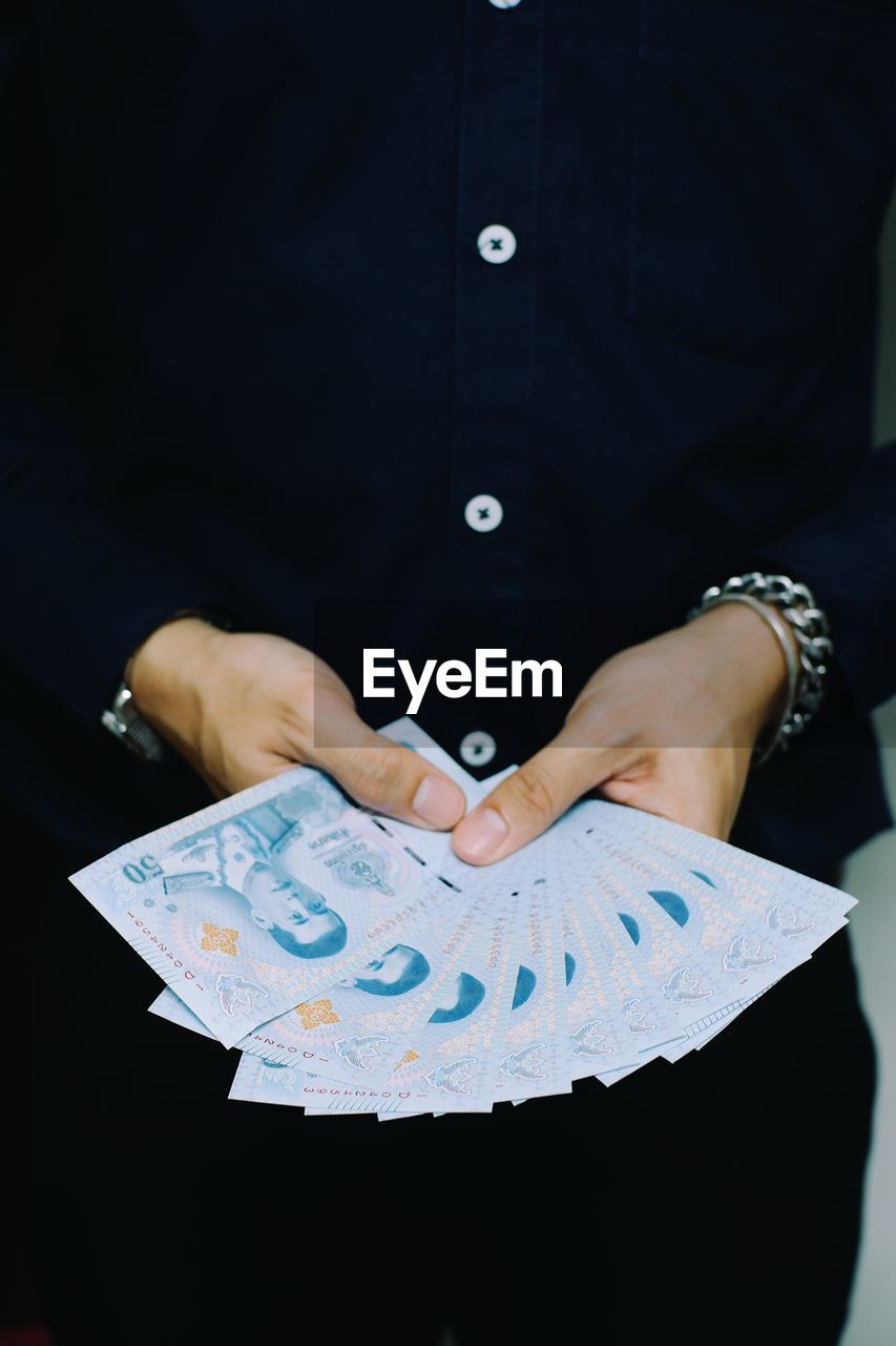 Midsection of man holding paper currency