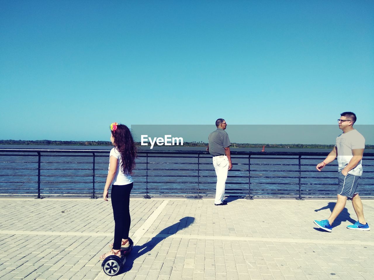 WOMAN STANDING AGAINST SEA AGAINST CLEAR SKY