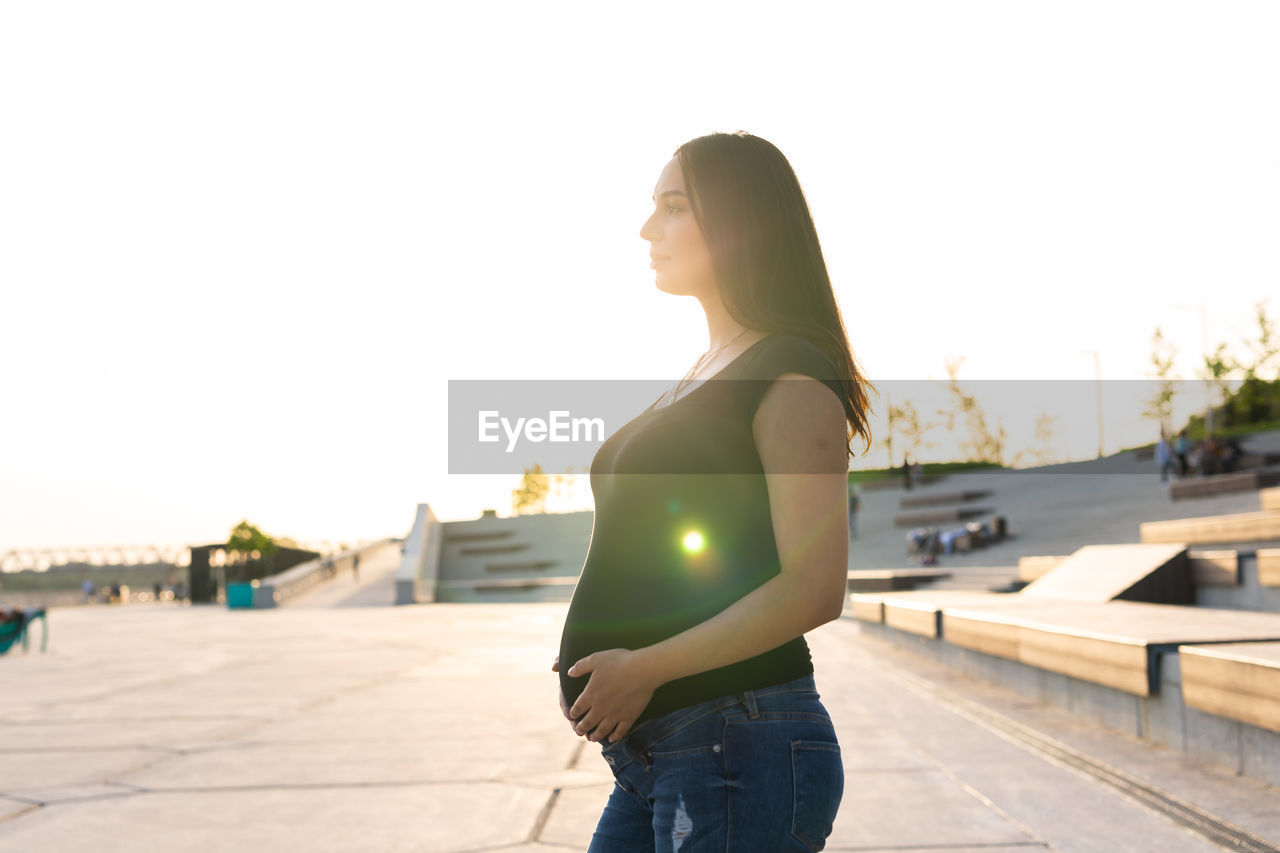 SIDE VIEW OF YOUNG WOMAN LOOKING AT CAMERA