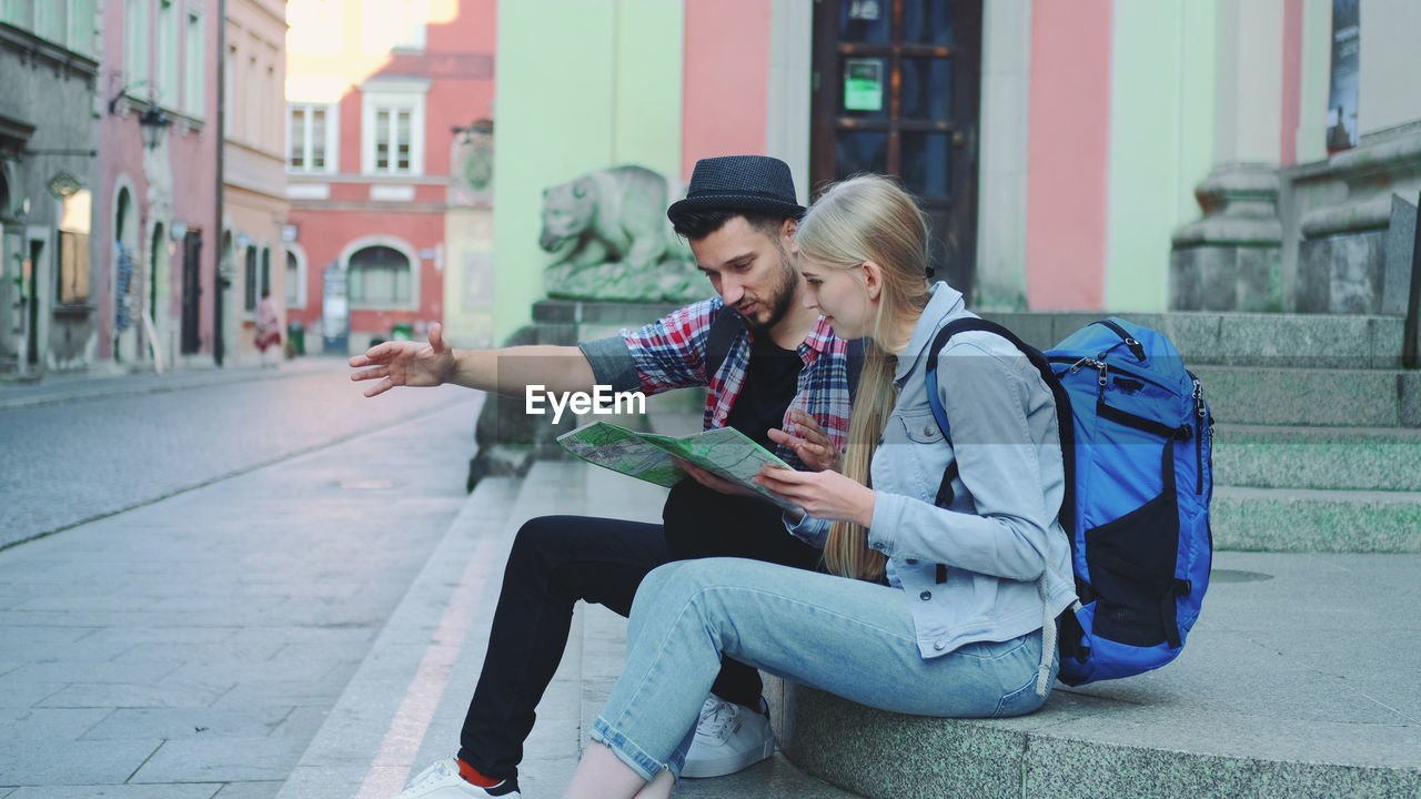 WOMAN USING PHONE WHILE SITTING ON CITY STREET