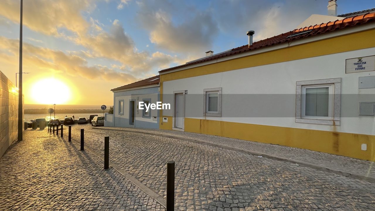 BUILDING BY SEA AGAINST SKY DURING SUNSET