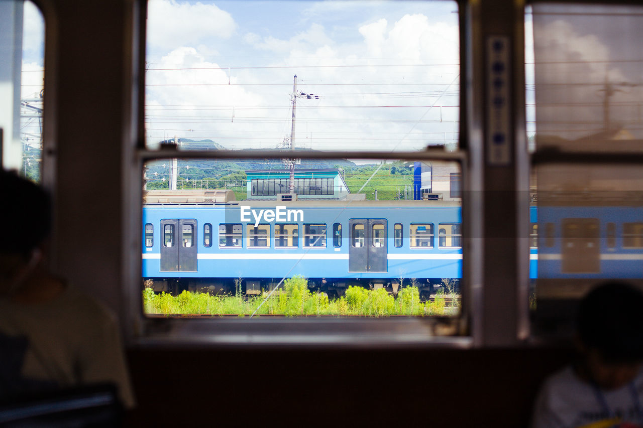 CLOSE-UP OF TRAIN WINDOW AGAINST SKY