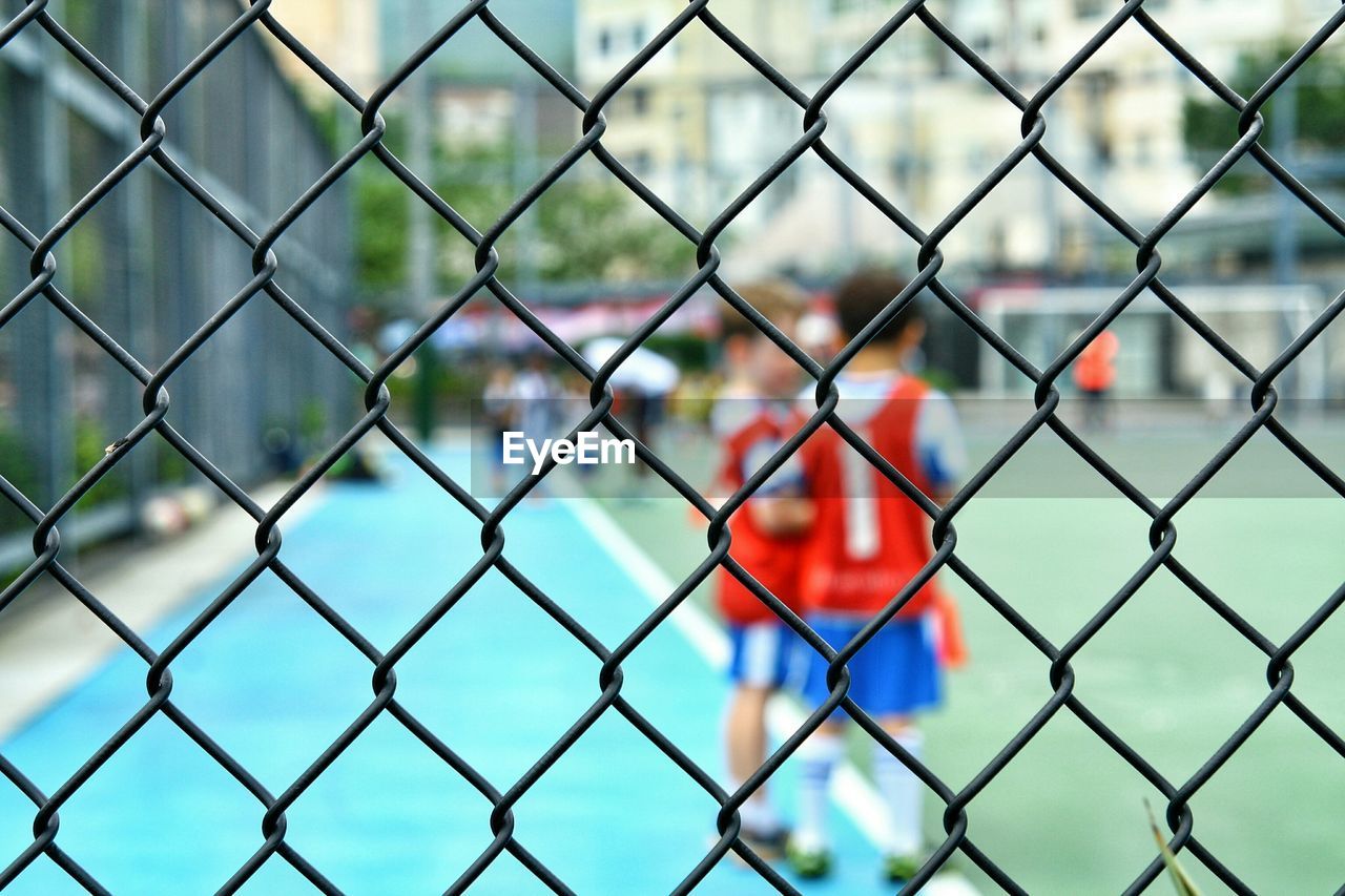 CLOSE-UP OF CHAINLINK FENCE AGAINST SKY SEEN THROUGH METAL GRATE