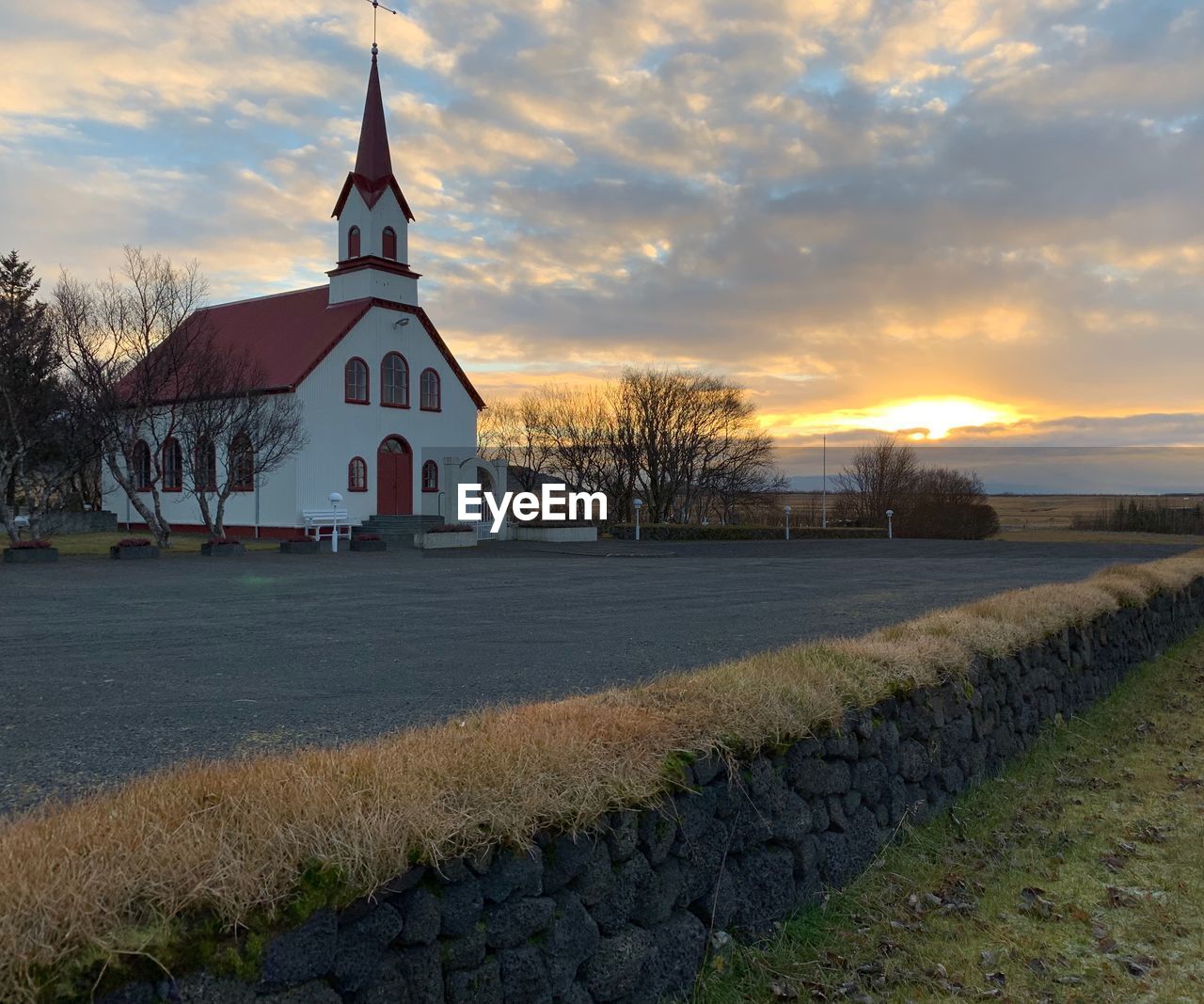 BUILDING ON FIELD AGAINST SKY AT SUNSET