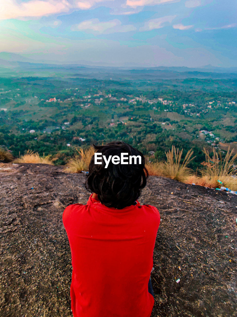 Rear view of man sitting on landscape against sky