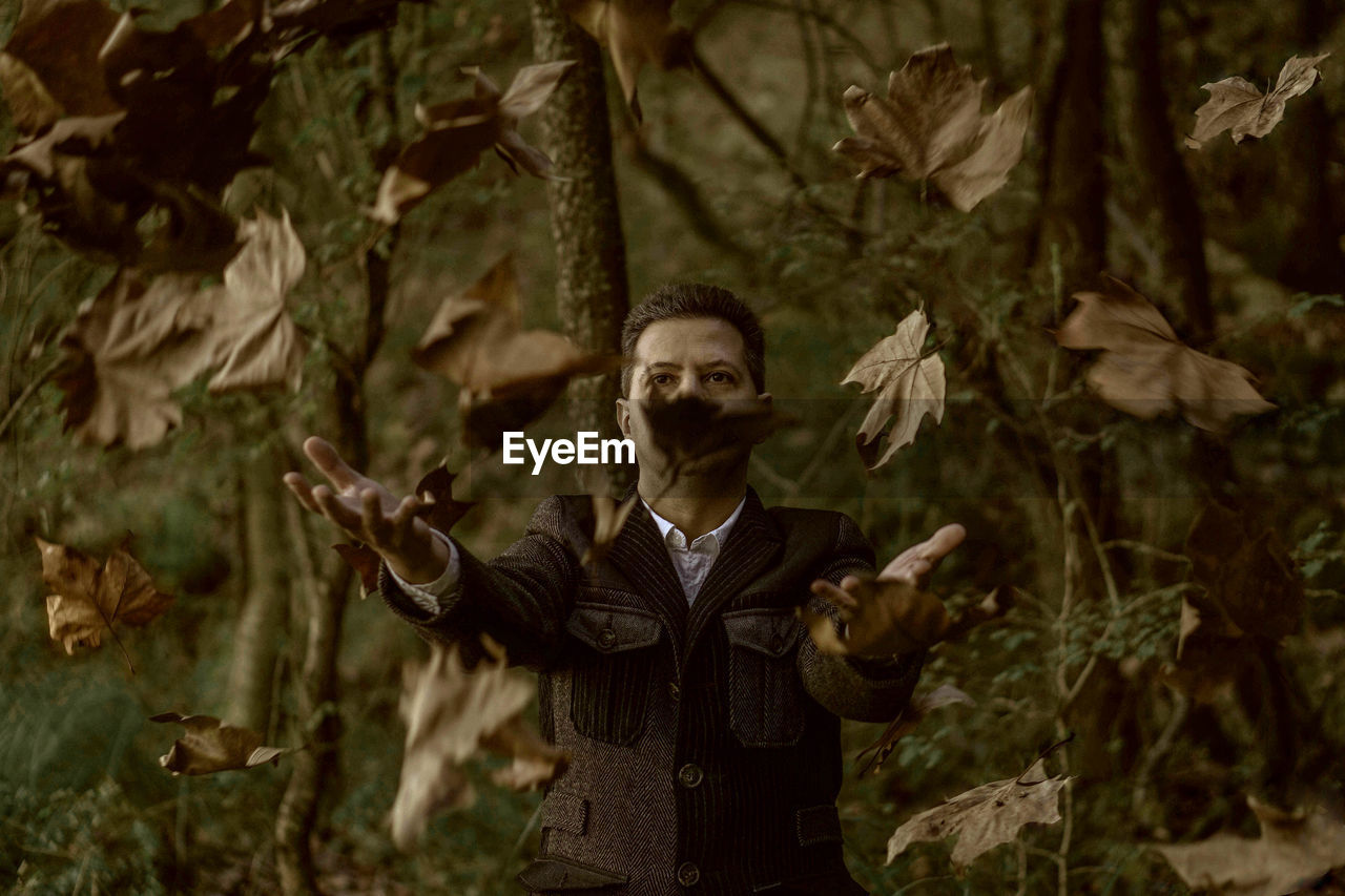 Man throwing autumn leaves in forest