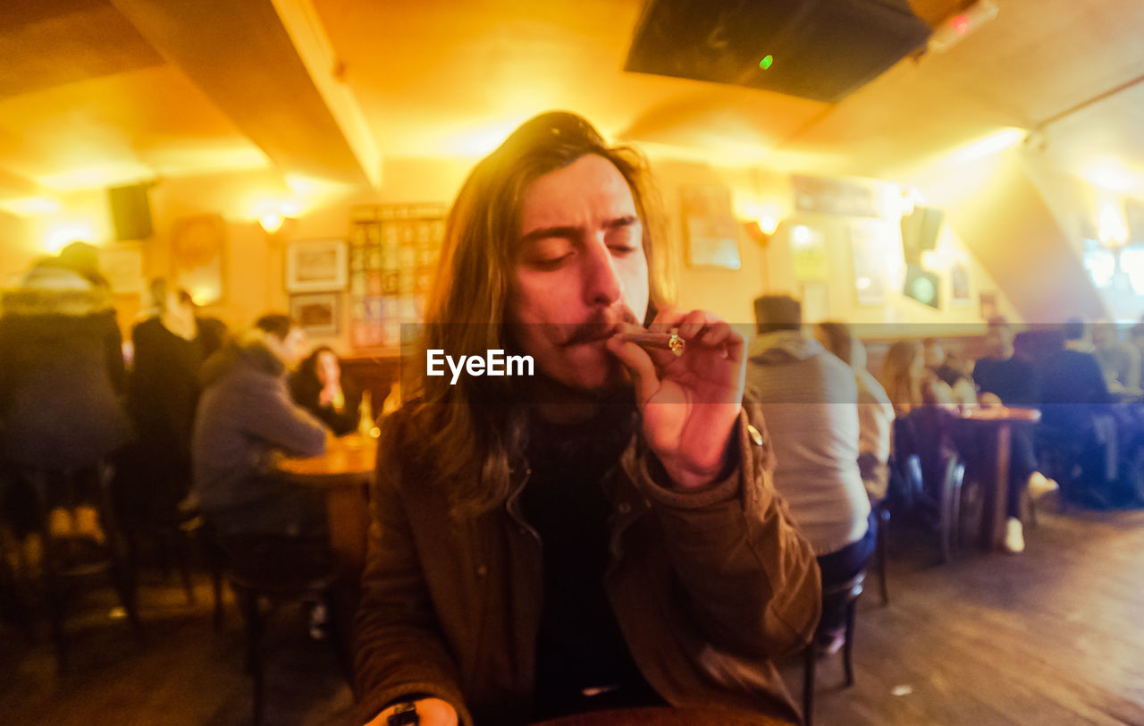 Young man smoking marijuana joint at restaurant