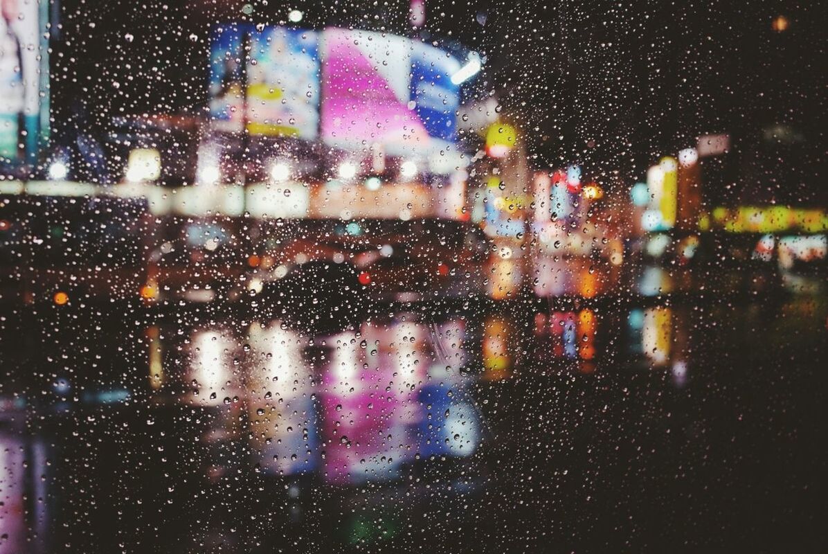 Close-up of waterdrops on glass against illuminated road at night