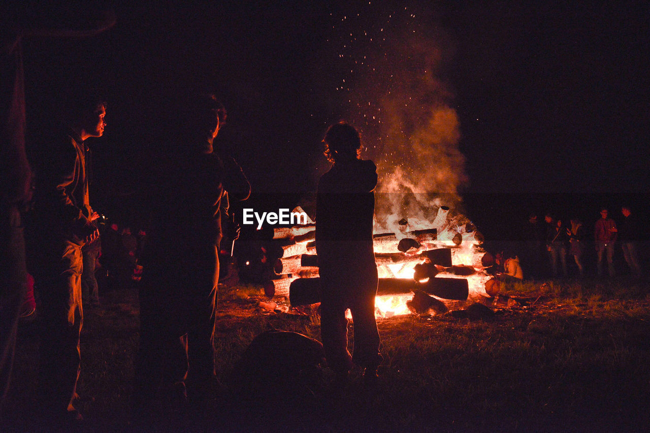 People standing around bonfire at night