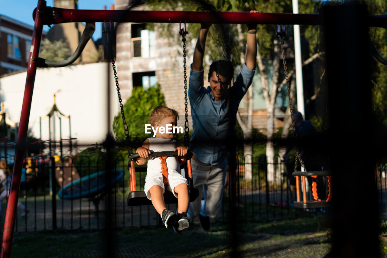 Girl with man swinging in playground