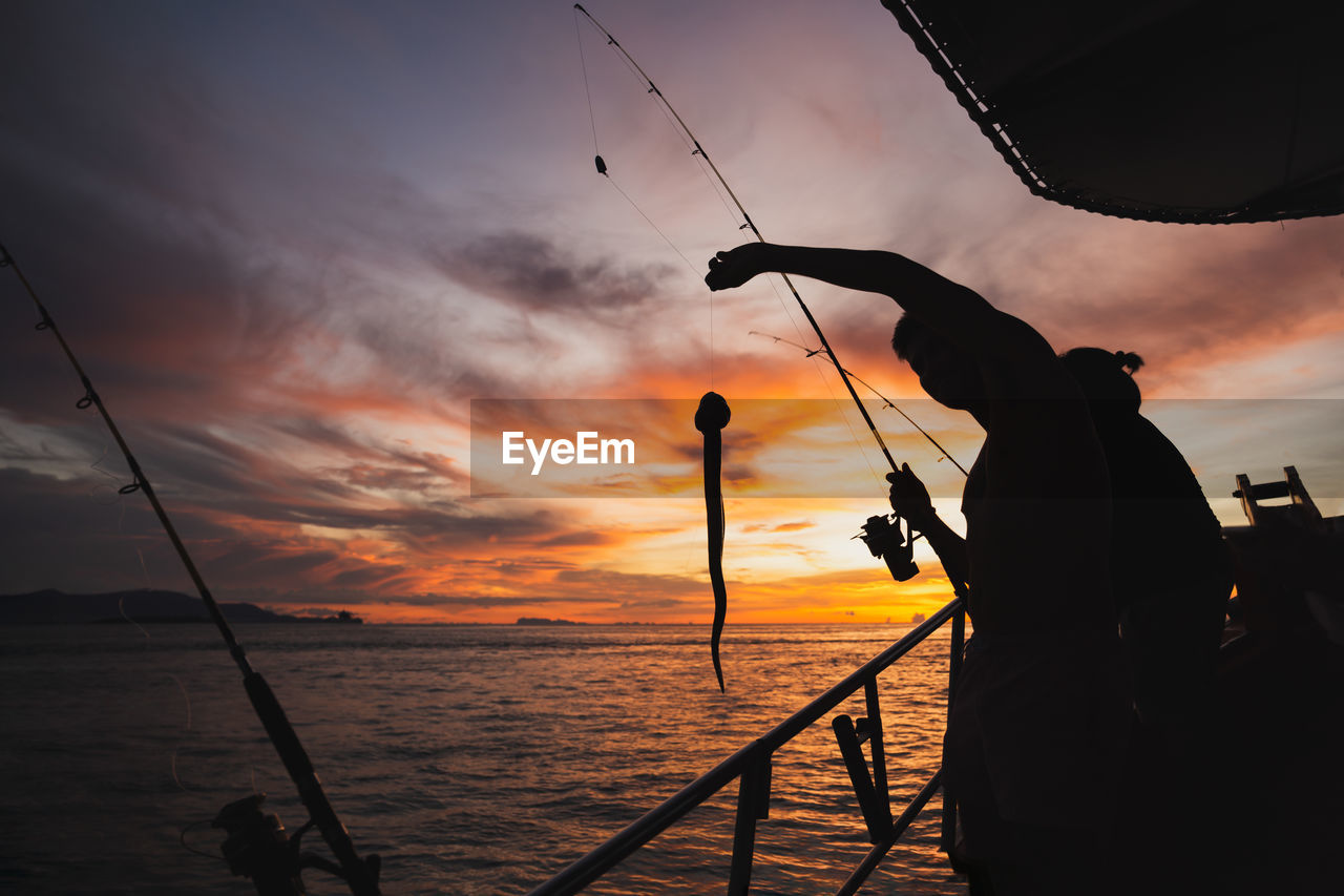 Silhouette young man fishing in open sea from the boat