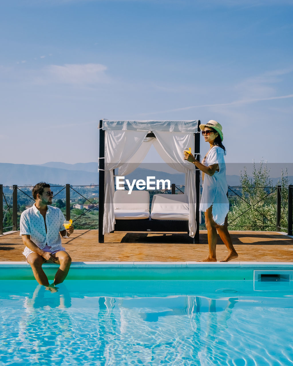 People sitting in swimming pool against blue sky