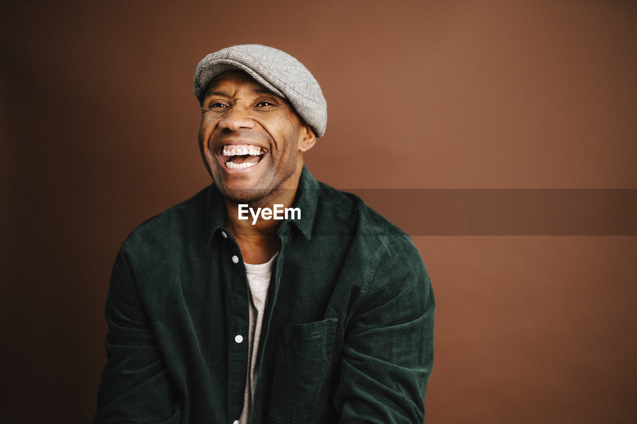 Mature man laughing against brown background in studio