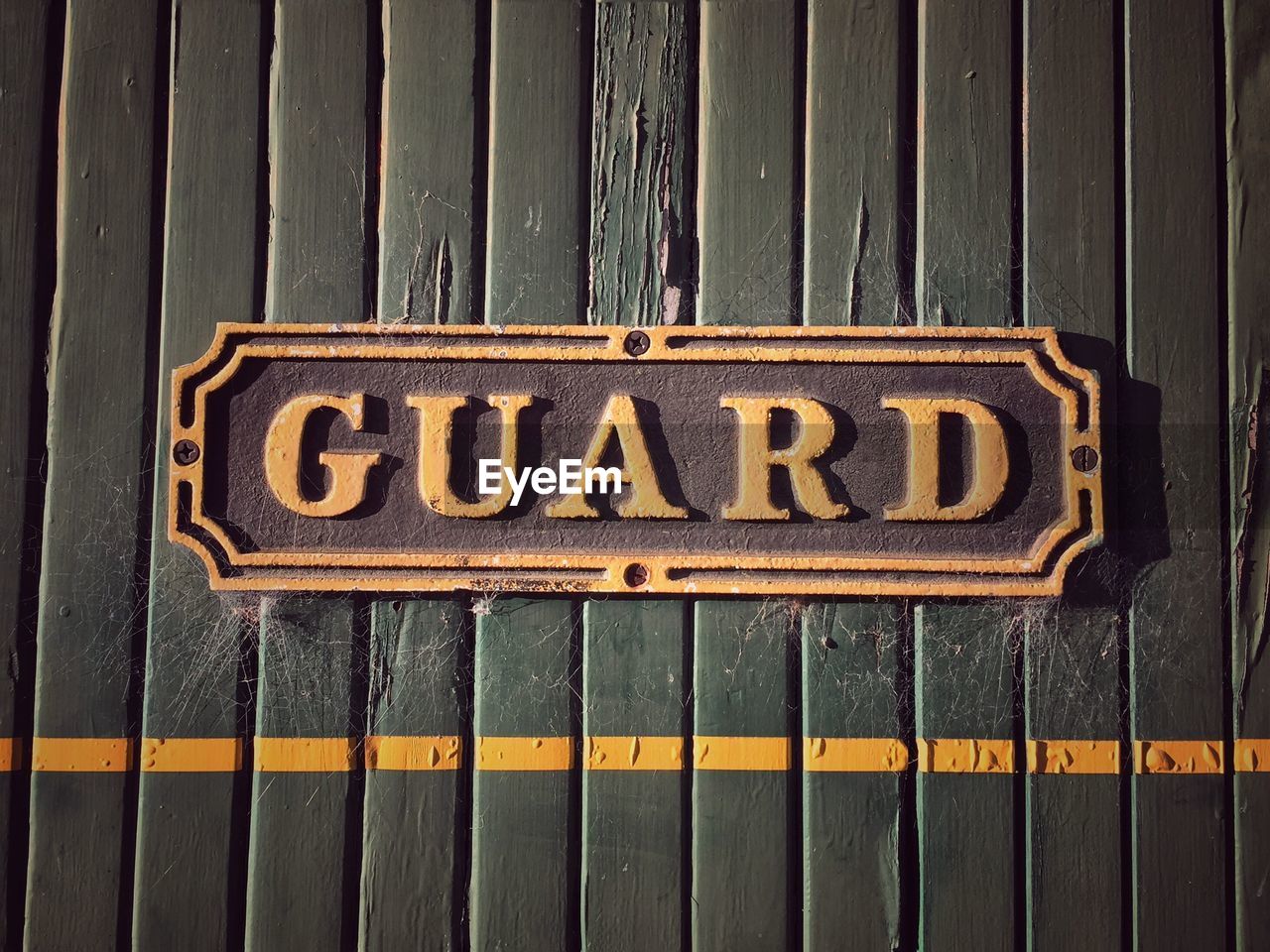 Close-up of metal with text mounted on wood of old train