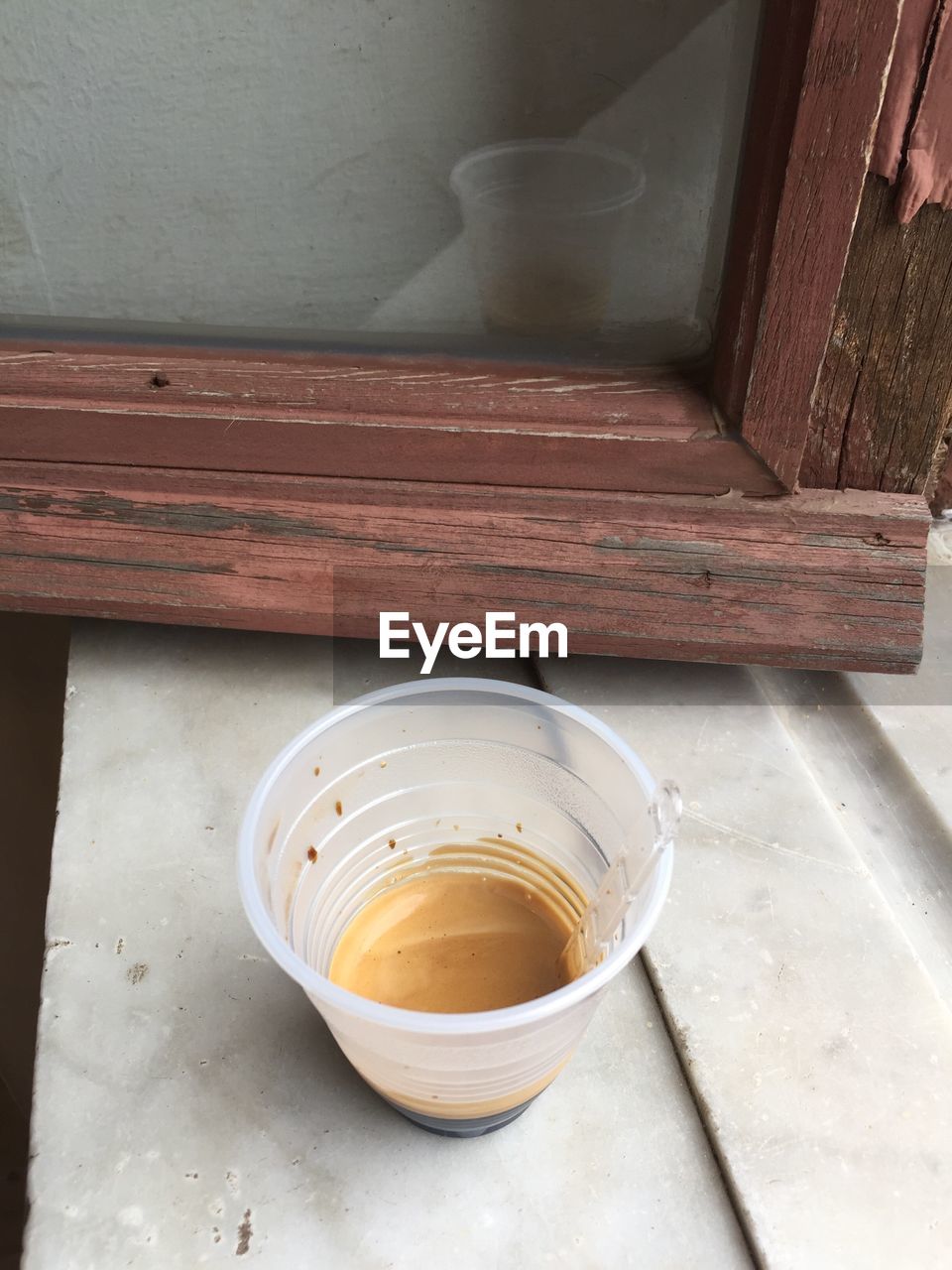 High angle view of leftover tea in disposable cup on window sill