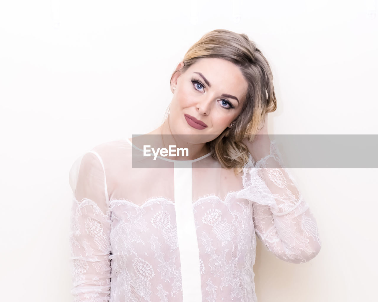 PORTRAIT OF YOUNG WOMAN AGAINST WHITE BACKGROUND