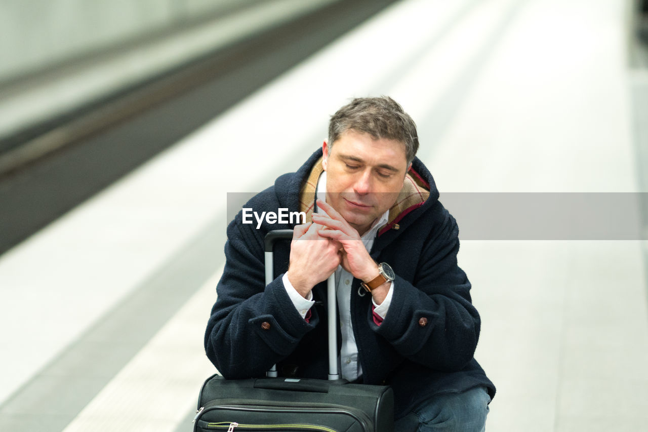 Man with luggage sleeping at railroad station platform