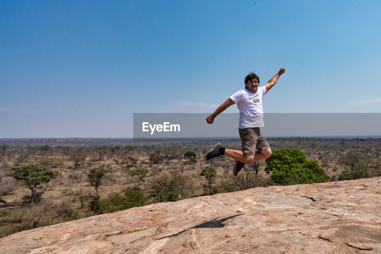 Full length of man jumping on landscape against clear sky