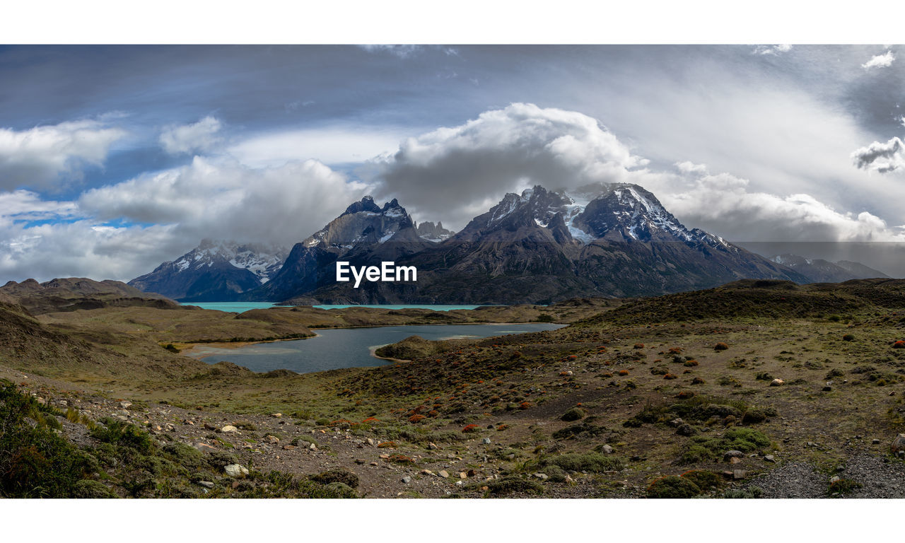 Scenic view of lake and mountains against cloudy sky