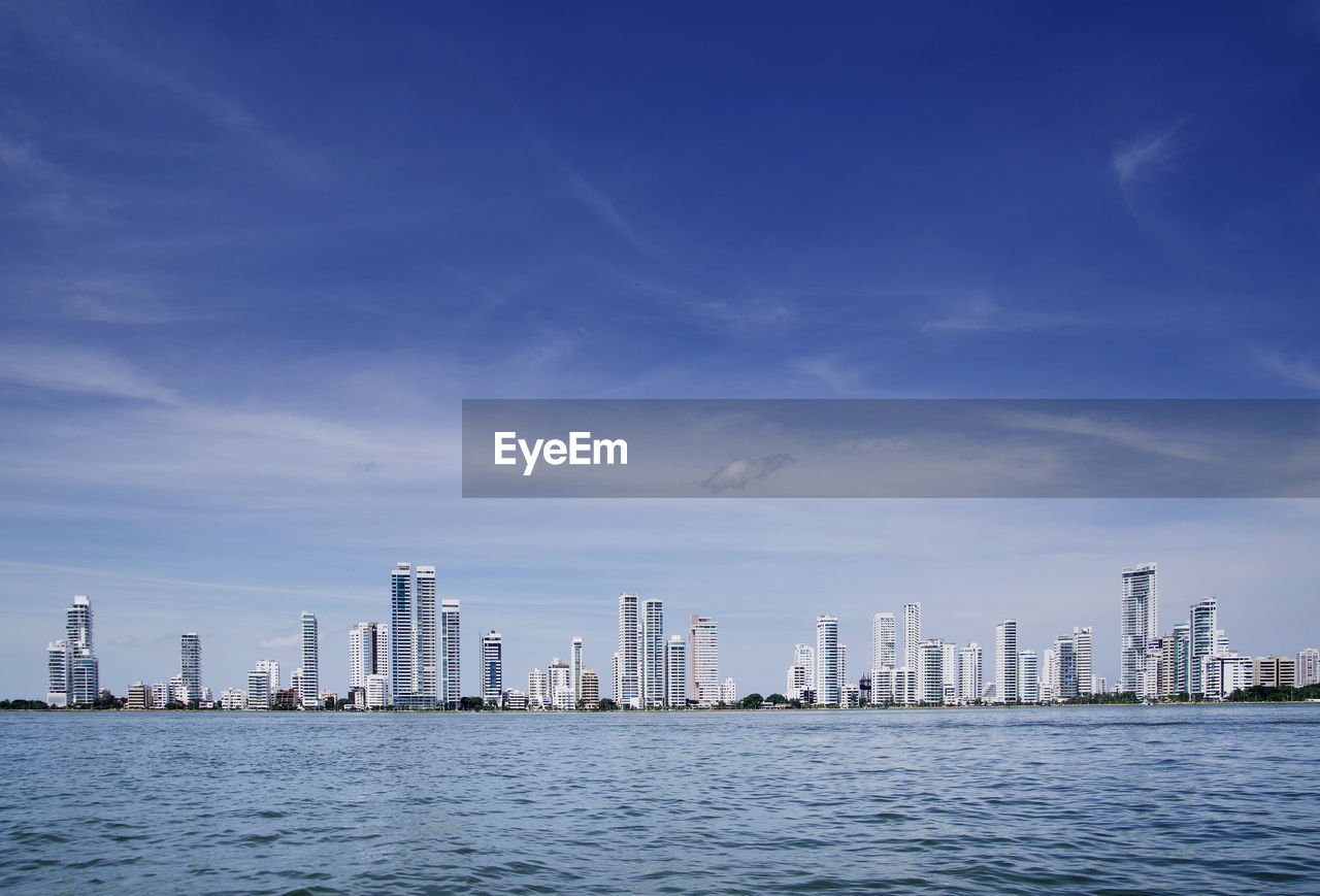 Sea by buildings against sky in city